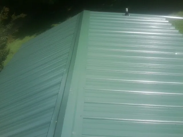New green metal panels meeting at the ridge of a roof — Flat Roof Repair work by our crew in Craig
