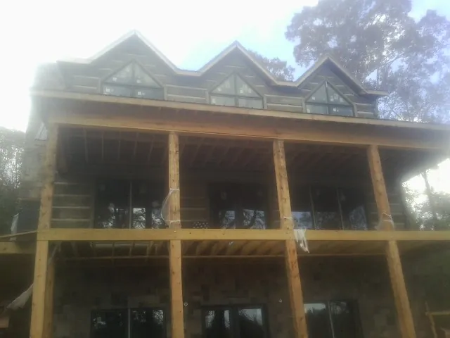 Dormers and porch framing on a large log home under construction — Roof Coating work by our crew in Craig