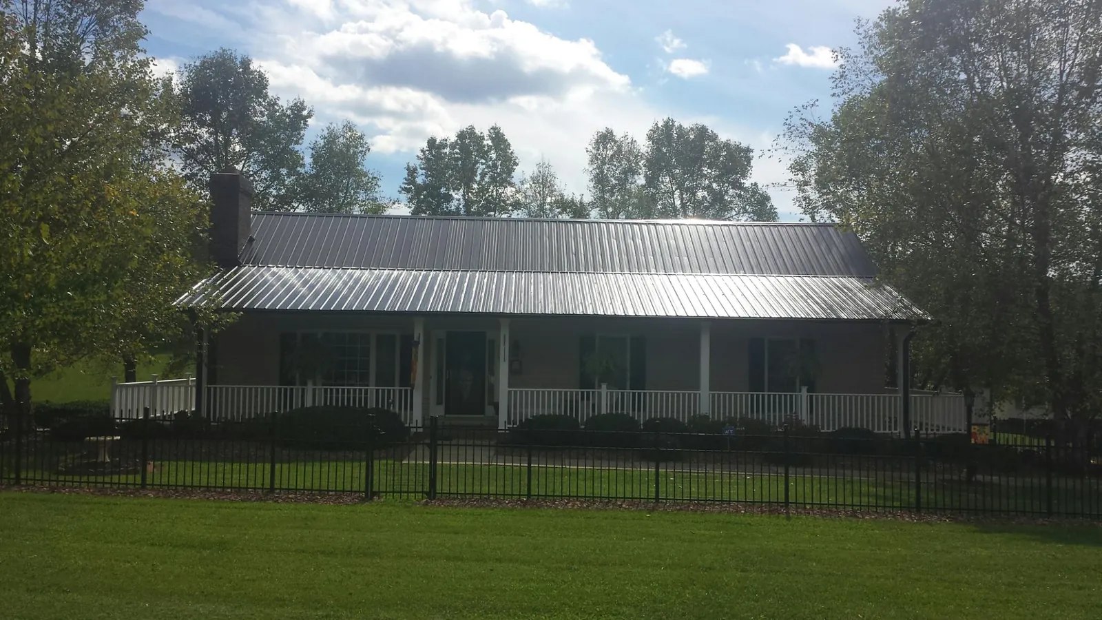 Gray metal roof on a brick ranch with a full width front porch — Gutter Guard Installation work by our crew in Craig
