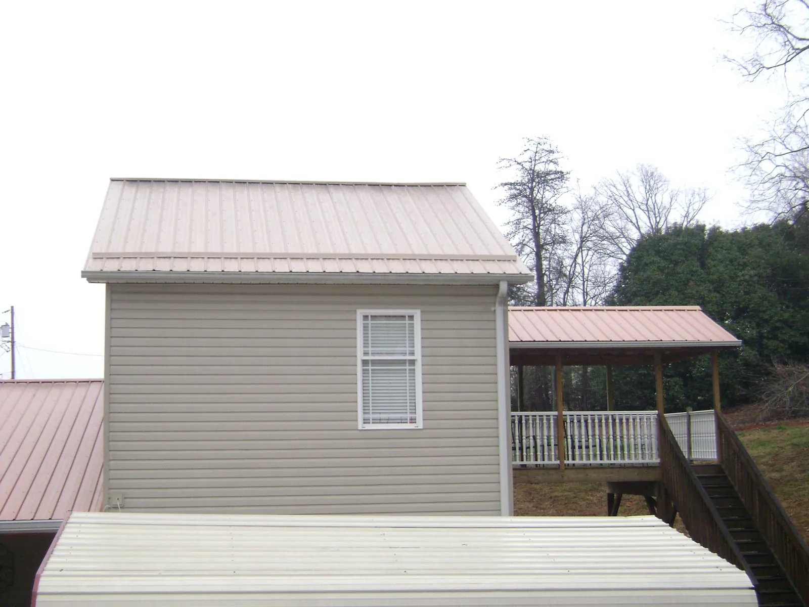 Tan metal roofs on a two story addition and attached porch, from a Roof Replacement job in Craig